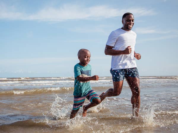Father and son running through ocean near Galveston Beach Resort in Texas.