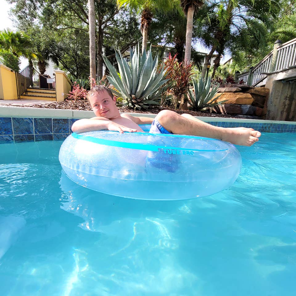 A young boy sits in an inner tube while floating down a lazy river.