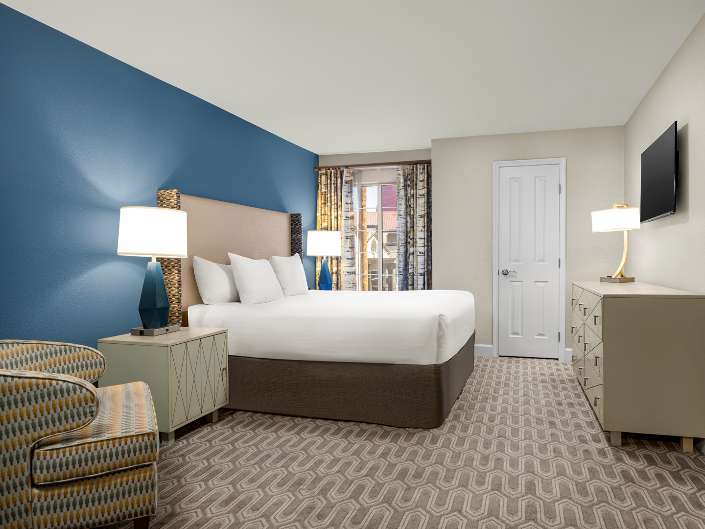 Bedroom with king bed, modern decor, and natural light.
