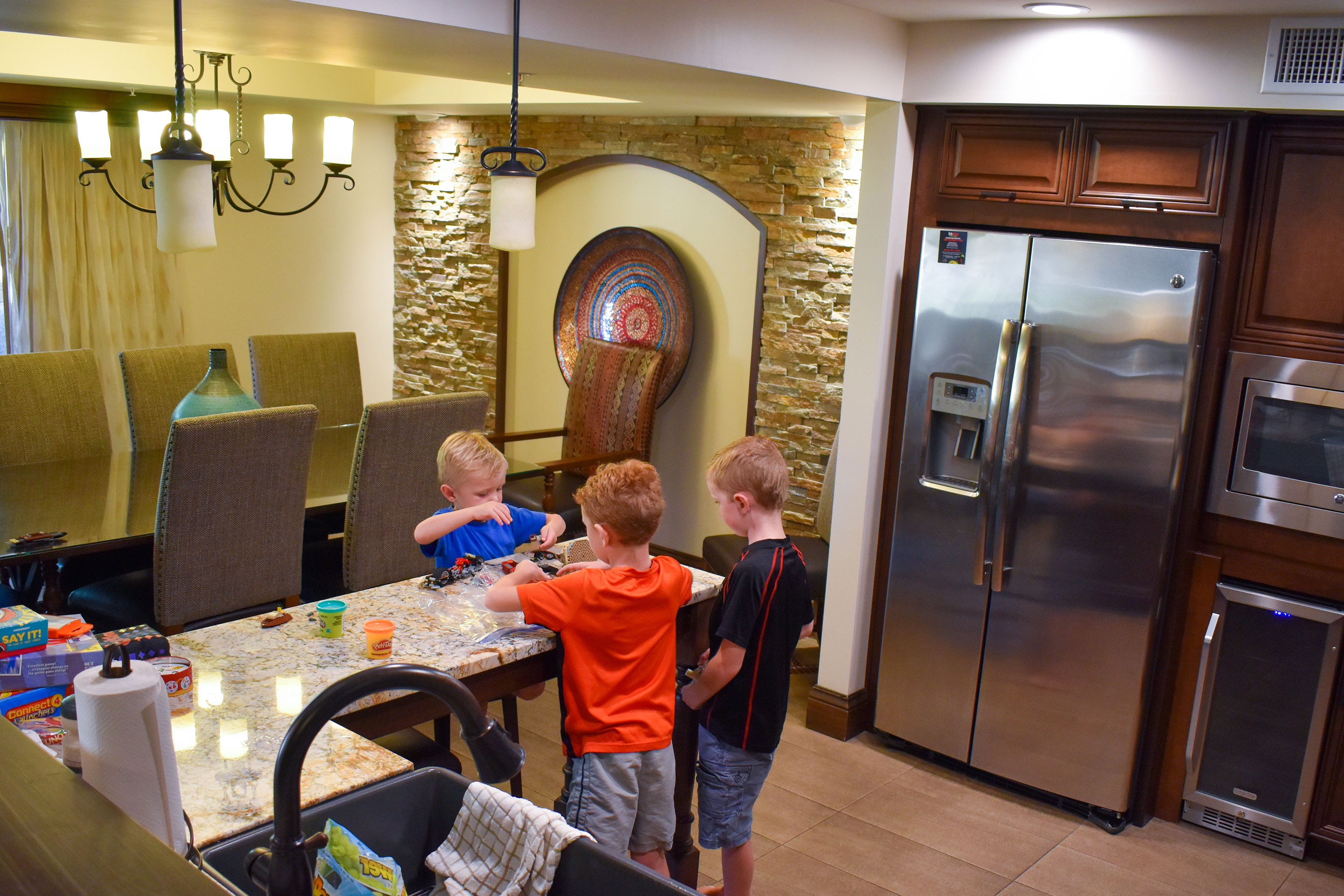The Averett boys play with toys on the kitchen countertop of our Scottsdale resort villa with a large dining room table and seating for several people in the background.