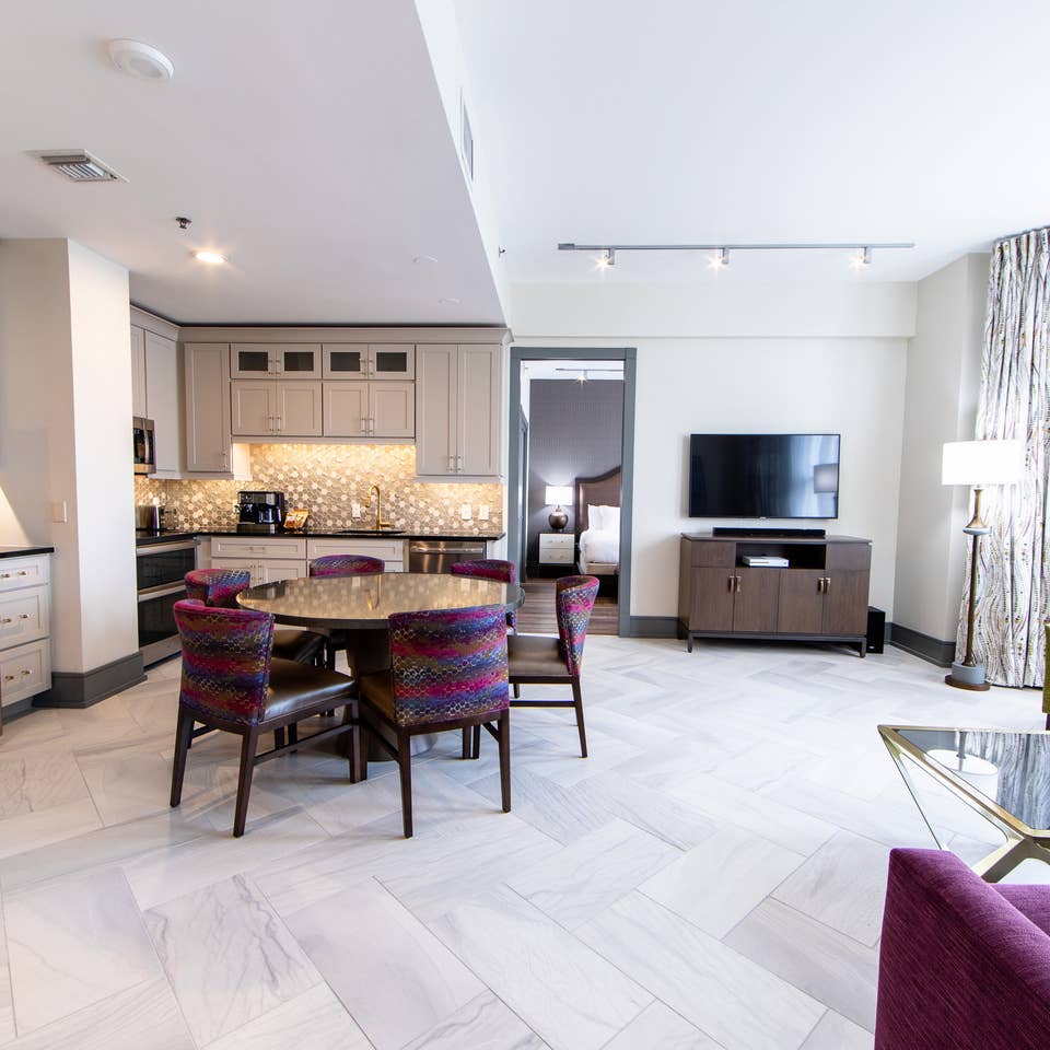 Signature Collection two bedroom villa living area with TV, dining area and full kitchen at New Orleans Resort in Louisiana.