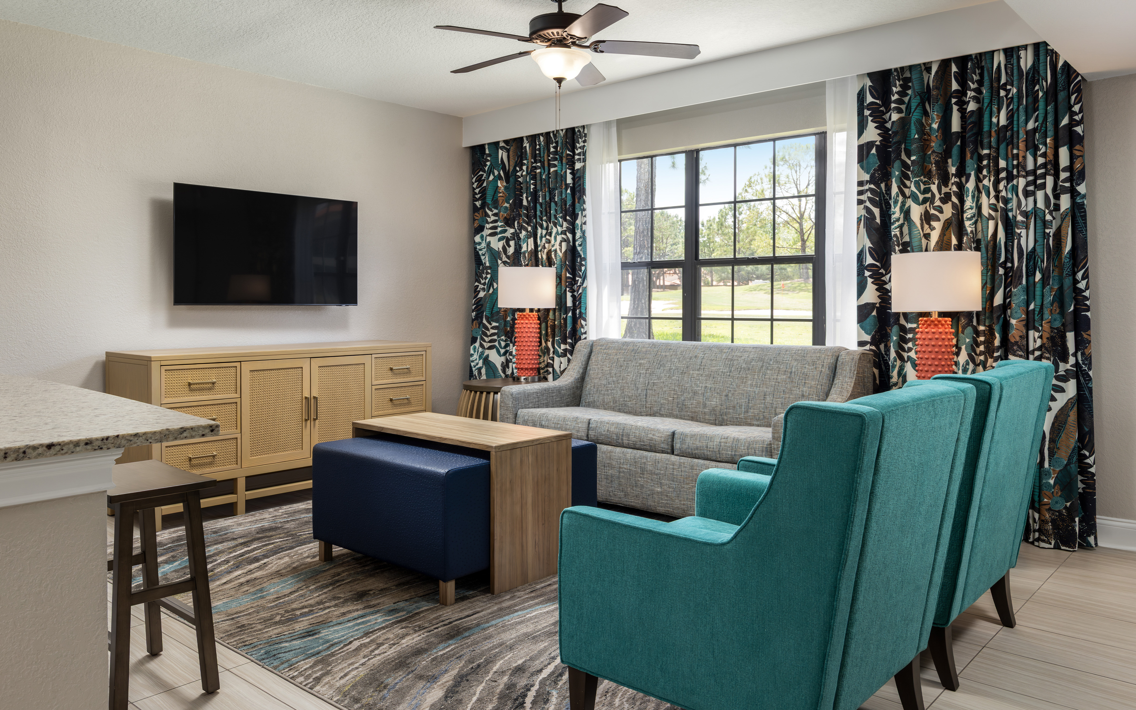 The renovated living room at Orange Lake Resort in Orlando, FL with a view of the golf course out of the paned window.