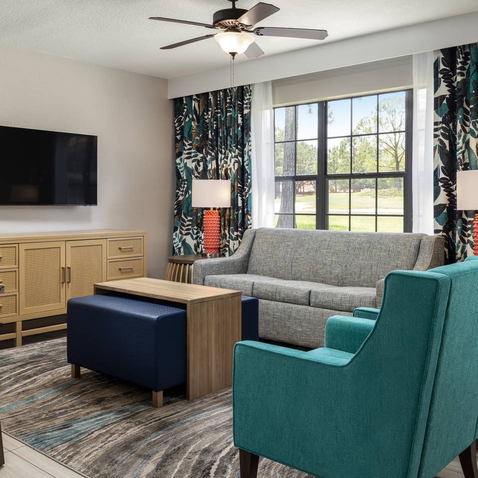 The renovated living room at Orange Lake Resort in Orlando, FL with a view of the golf course out of the paned window.
