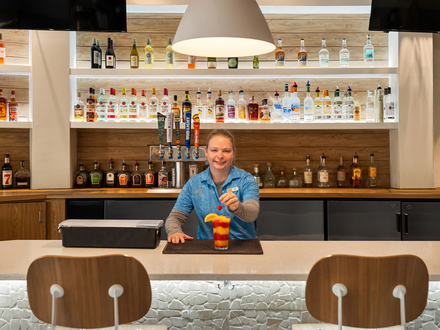 Bartender making a drink in an indoor bar at Cape Grill & Bar at Cape Canaveral Beach Resort.