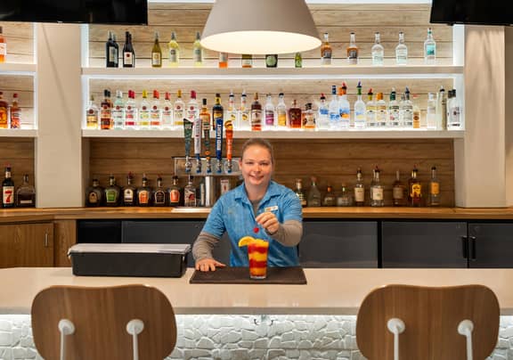 Bartender making a drink in an indoor bar at Cape Grill & Bar at Cape Canaveral Beach Resort.
