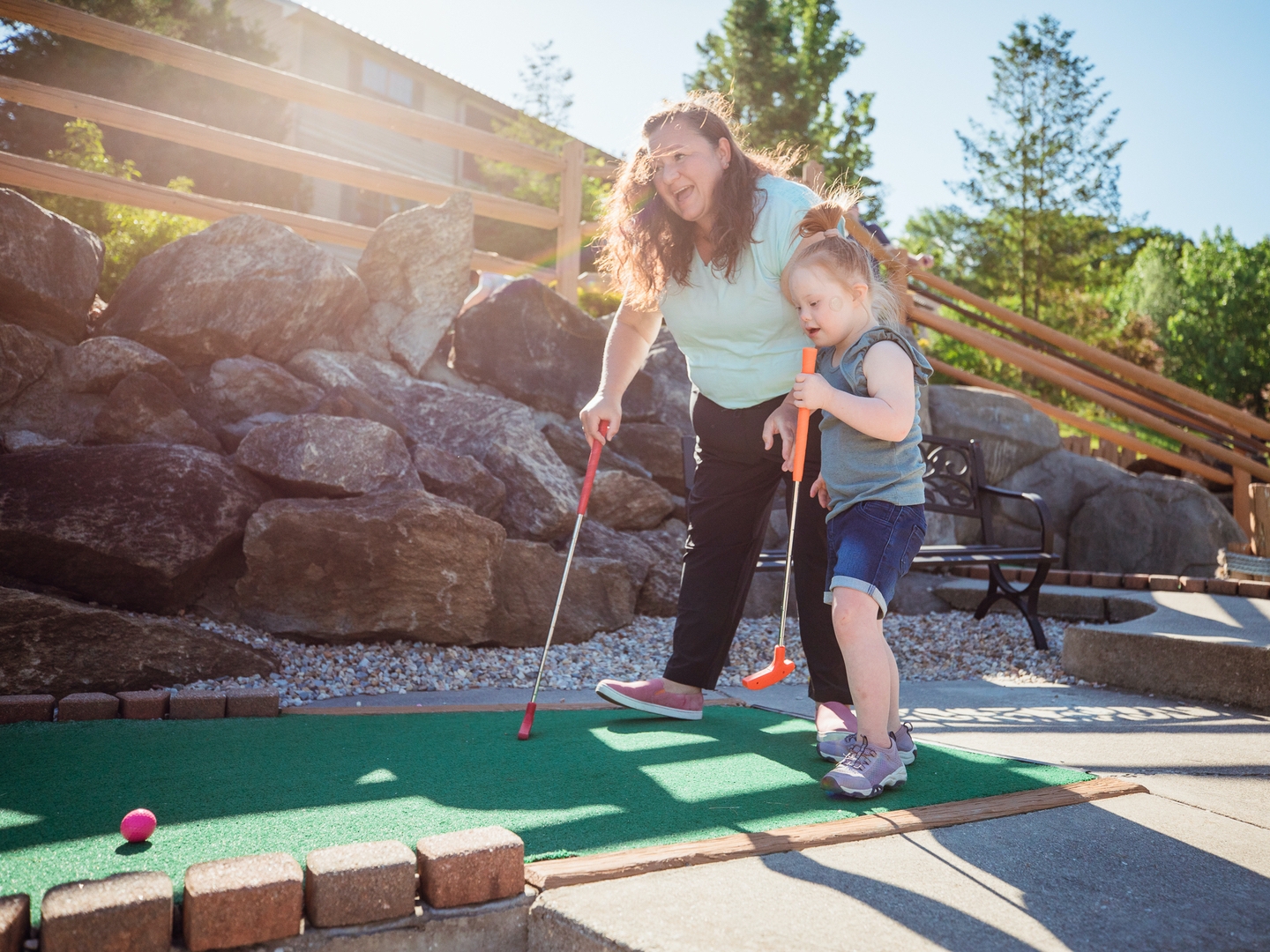 Mother and daughter playing mini golf outdoors at Oak n' Spruce Resort in South Lee, Massachusetts.