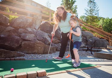 Mother and daughter playing mini golf outdoors at Oak n' Spruce Resort in South Lee, Massachusetts.