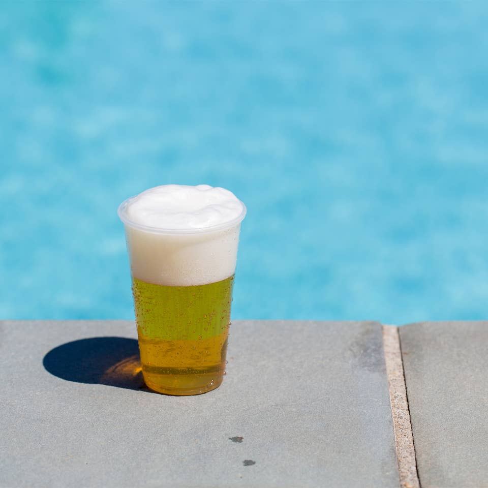 Glass of beer by an outdoor pool.