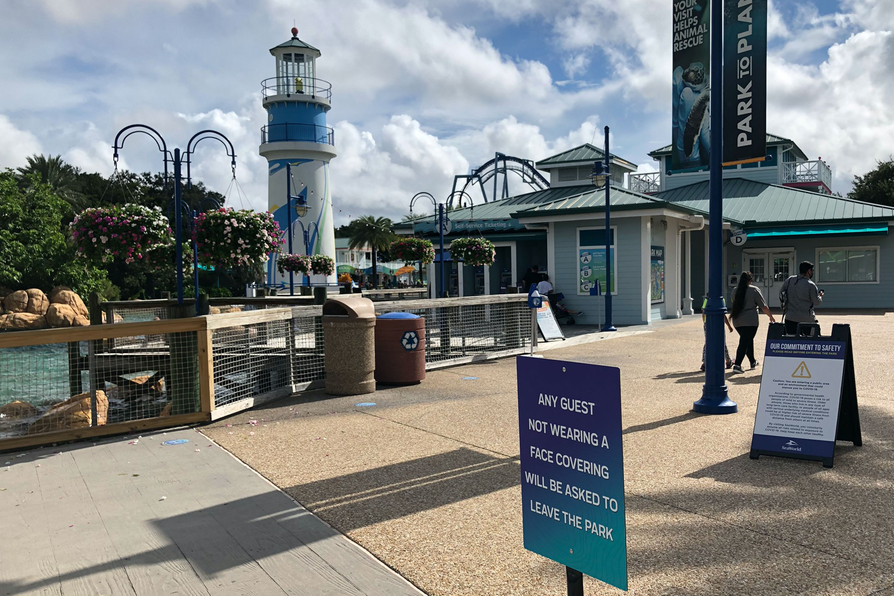 SeaWorld Orlando lighthouse and boardwalk entrance clad with safety signage to enforce social distancing.
