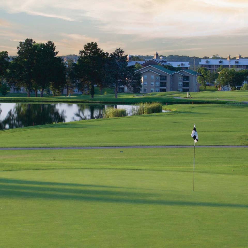 Golf course with property buildings and lake in the background at Holiday Hills Resort in Branson, Missouri.