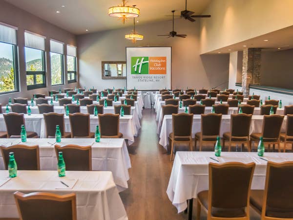 Round tables with white tablecloths set up in an event venue with view of mountains at Tahoe Ridge Resort in Stateline, Nevada.