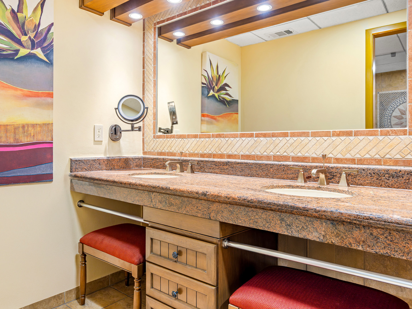 Bathroom with a double vanity, large mirror, and plush seating.