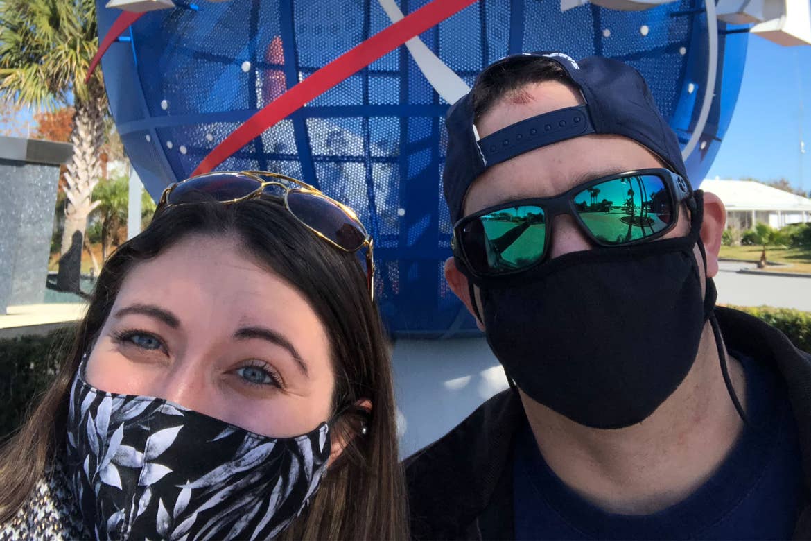 Featured contributor and Checking In editor, Tori Ferrante (left), and her husband, Brooks (right) wear masks in front of the NASA globe outside of Kennedy Space Center in Cape Canaveral, Florida.