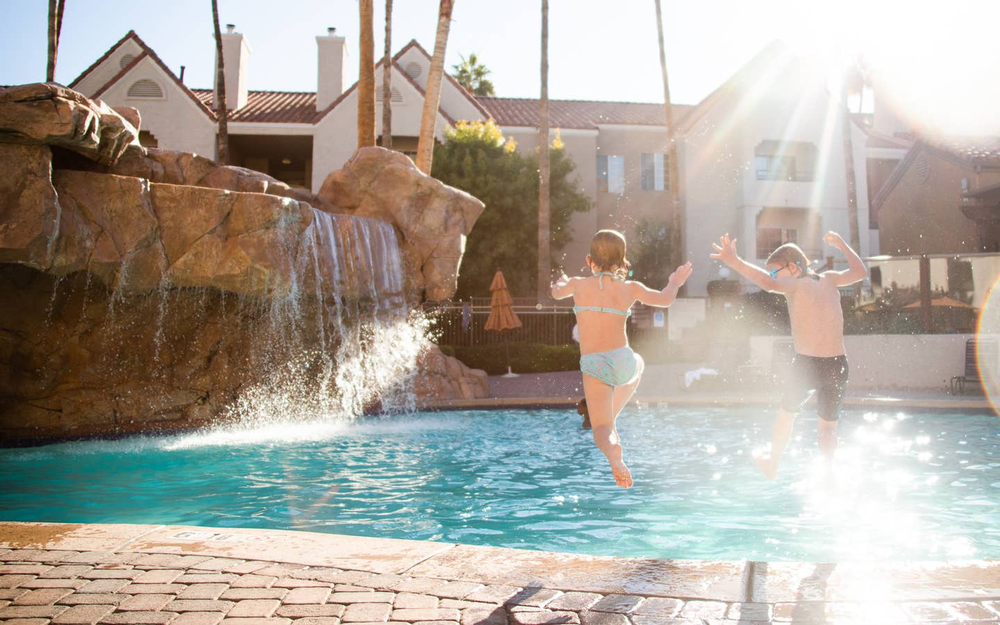Two kids jumping into outdoor pool at Desert Club Resort in Las Vegas, Nevada.