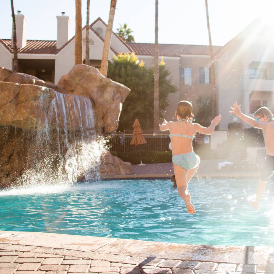 Two kids jumping into outdoor pool at Desert Club Resort in Las Vegas, Nevada.
