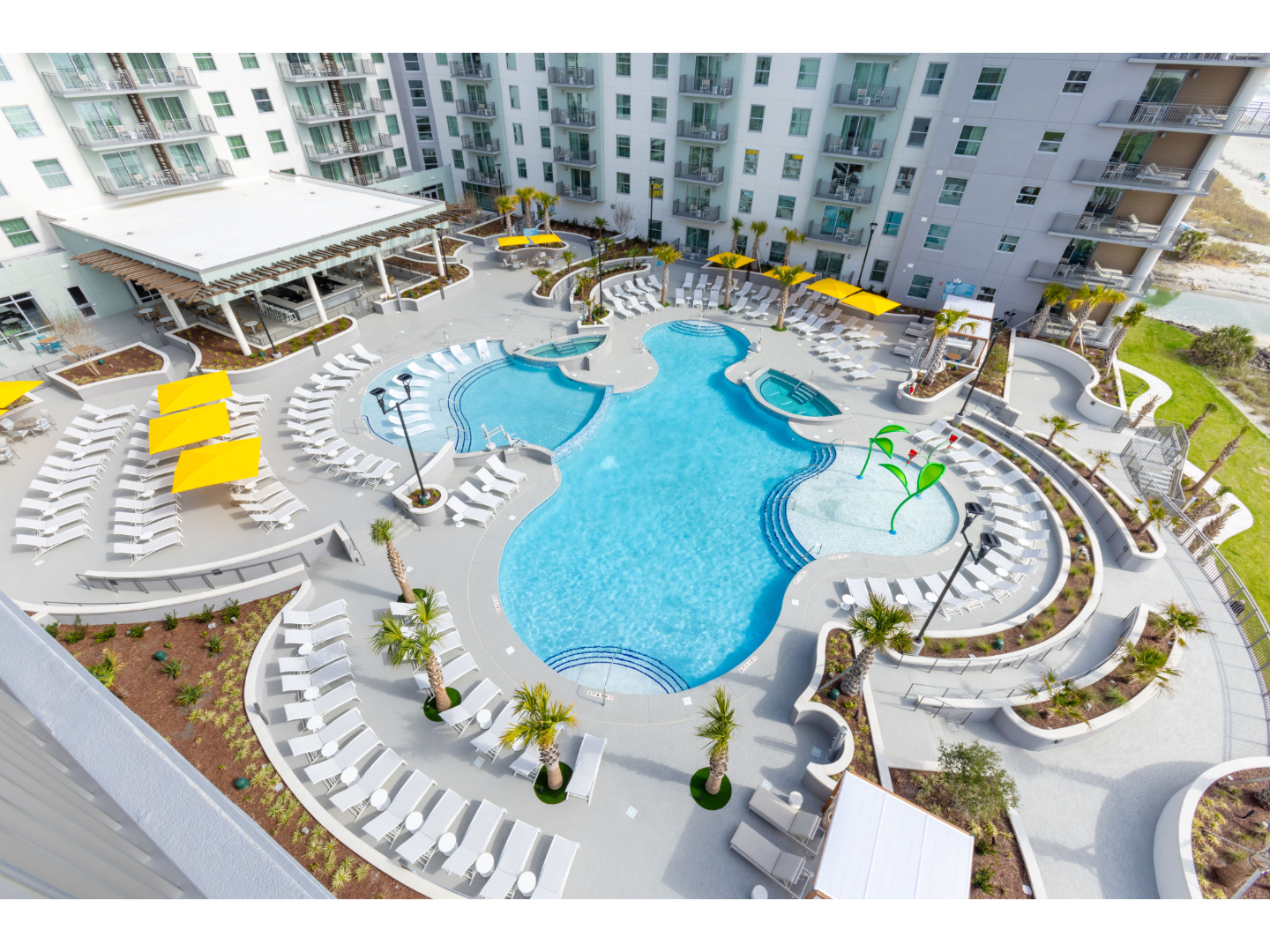 Aerial view of pool with gray pavement and crisp white buildings.