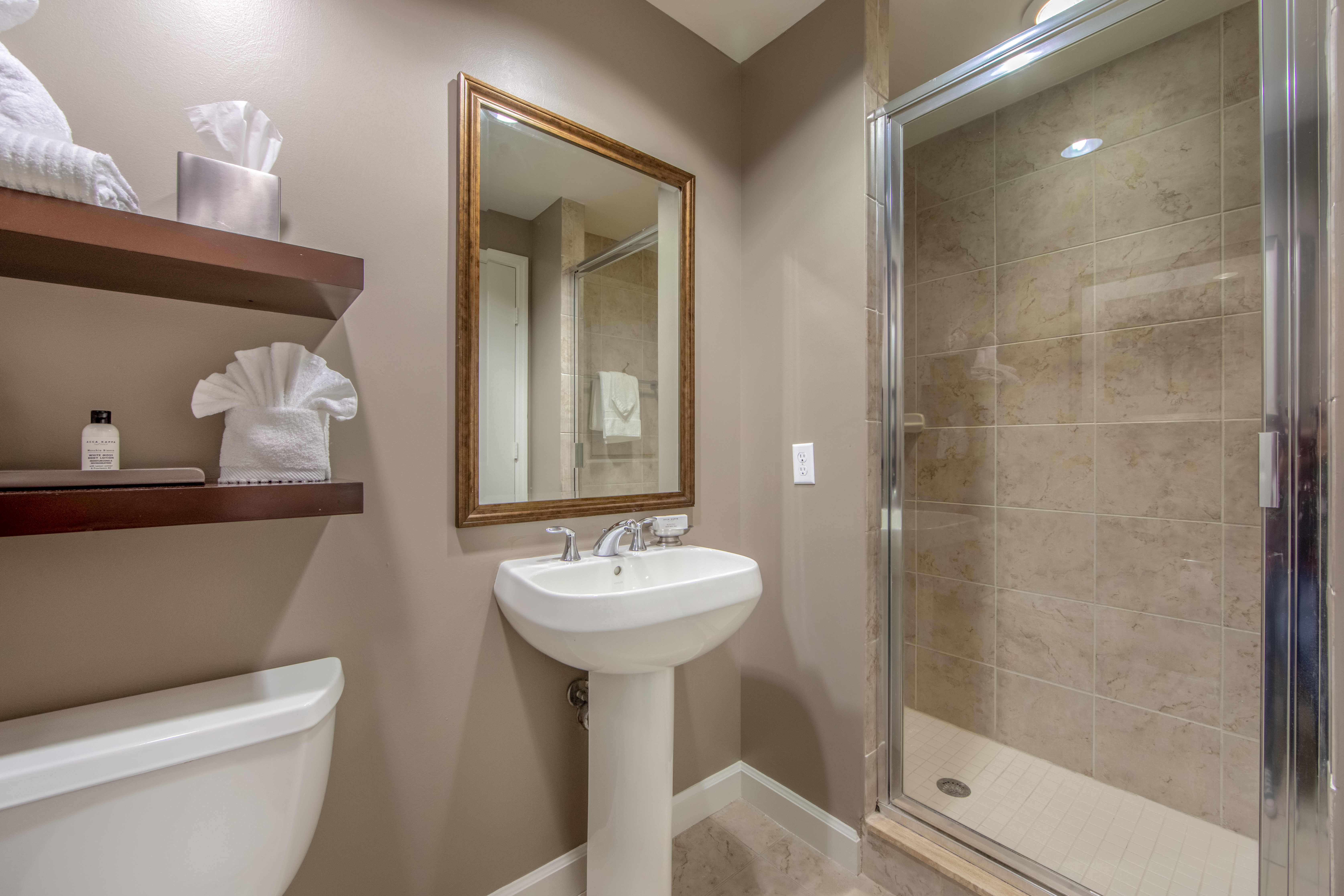Bathroom with walk-in shower, sink with mirror above, and toilet in a three-bedroom villa at Sunset Cove Resort in Marco Island, Florida