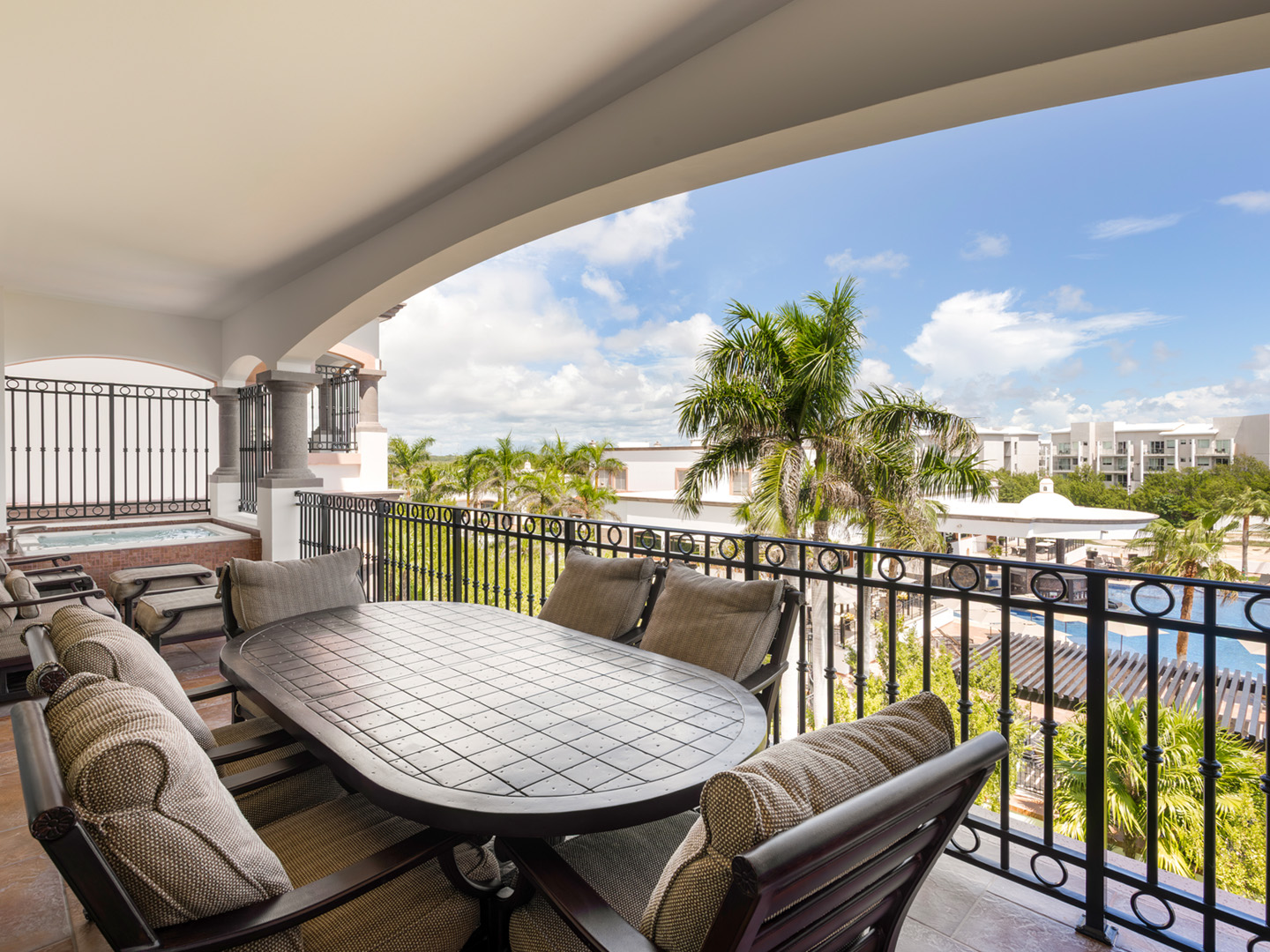 Balcony dining area with lounge chairs and lush resort scenery.