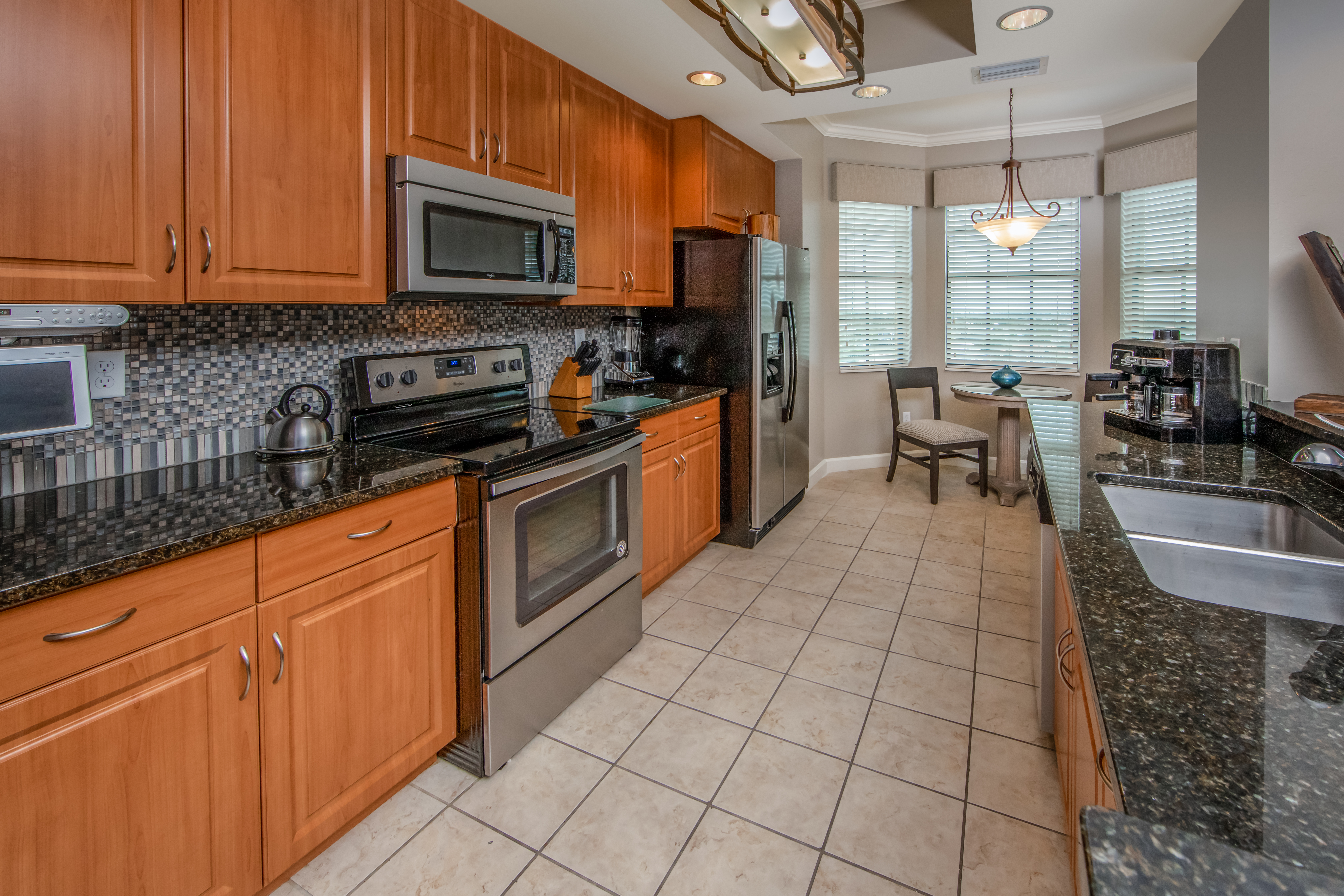 Full kitchen with stainless steel oven, microwave, fridge, and sink in a three-bedroom villa at Sunset Cove Resort in Marco Island, Florida