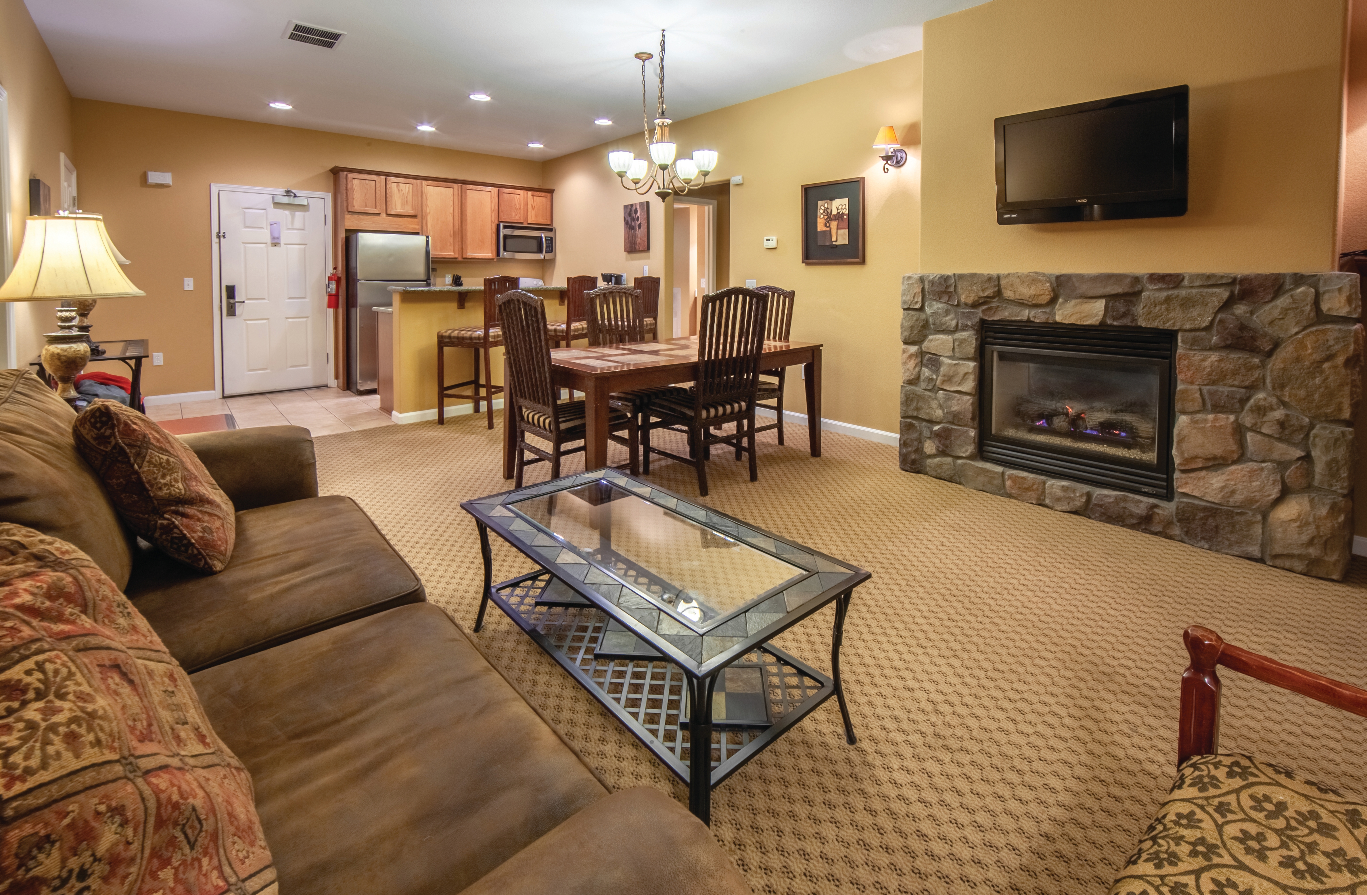 Living room with fireplace and a view of the dining area and full kitchen in a two-bedroom villa at David Walley's Resort in Genoa, Nevada