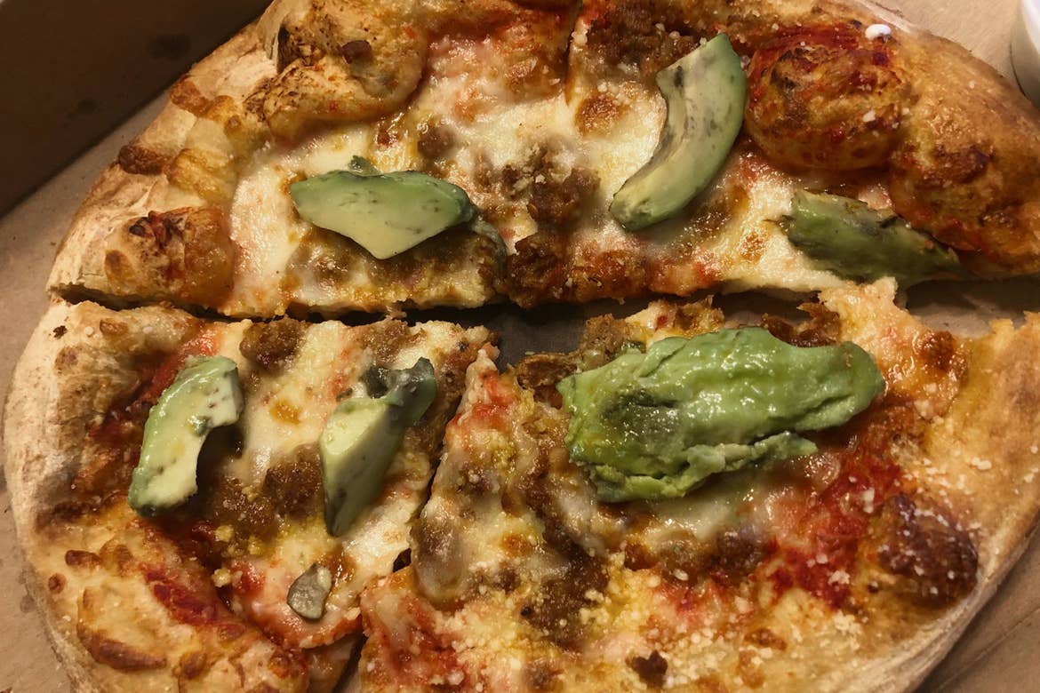 A pizza topped with cheese and avocado slices.