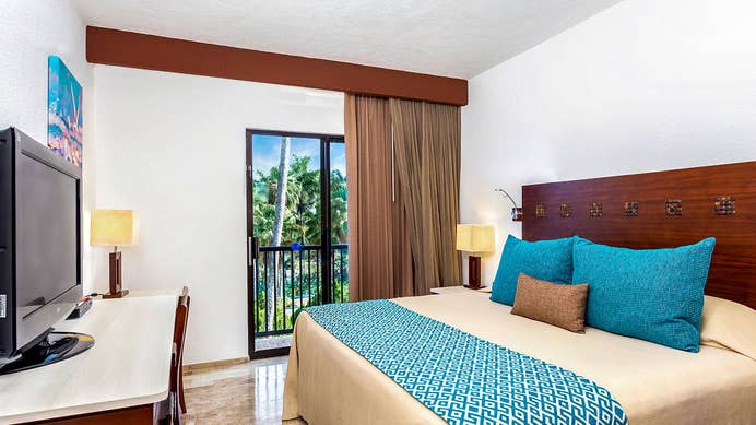 Bedroom with a window view of palm trees at The Royal Cancun in Mexico.