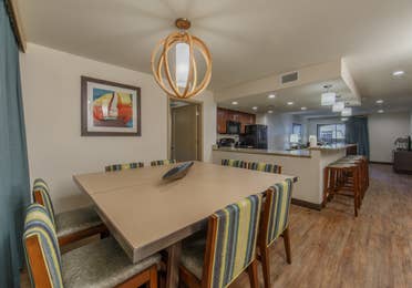 Dining table with eight chairs and kitchen in background in a three-bedroom villa at Scottsdale Resort