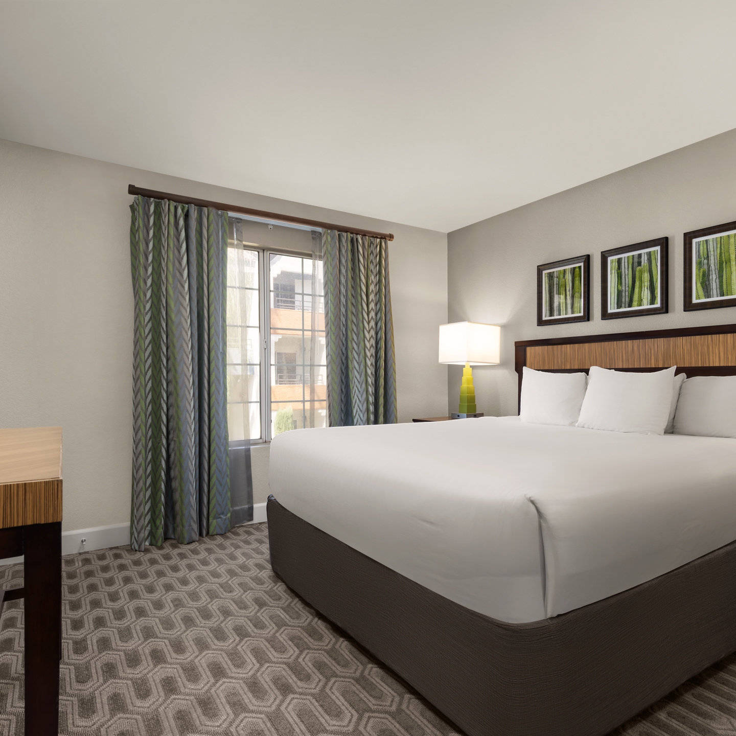 Bright, modern bedroom featuring a plush king bed and warm accents.
