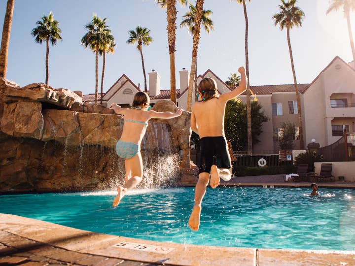 Two kids jumping into outdoor pool at Desert Club Resort in Las Vegas, Nevada