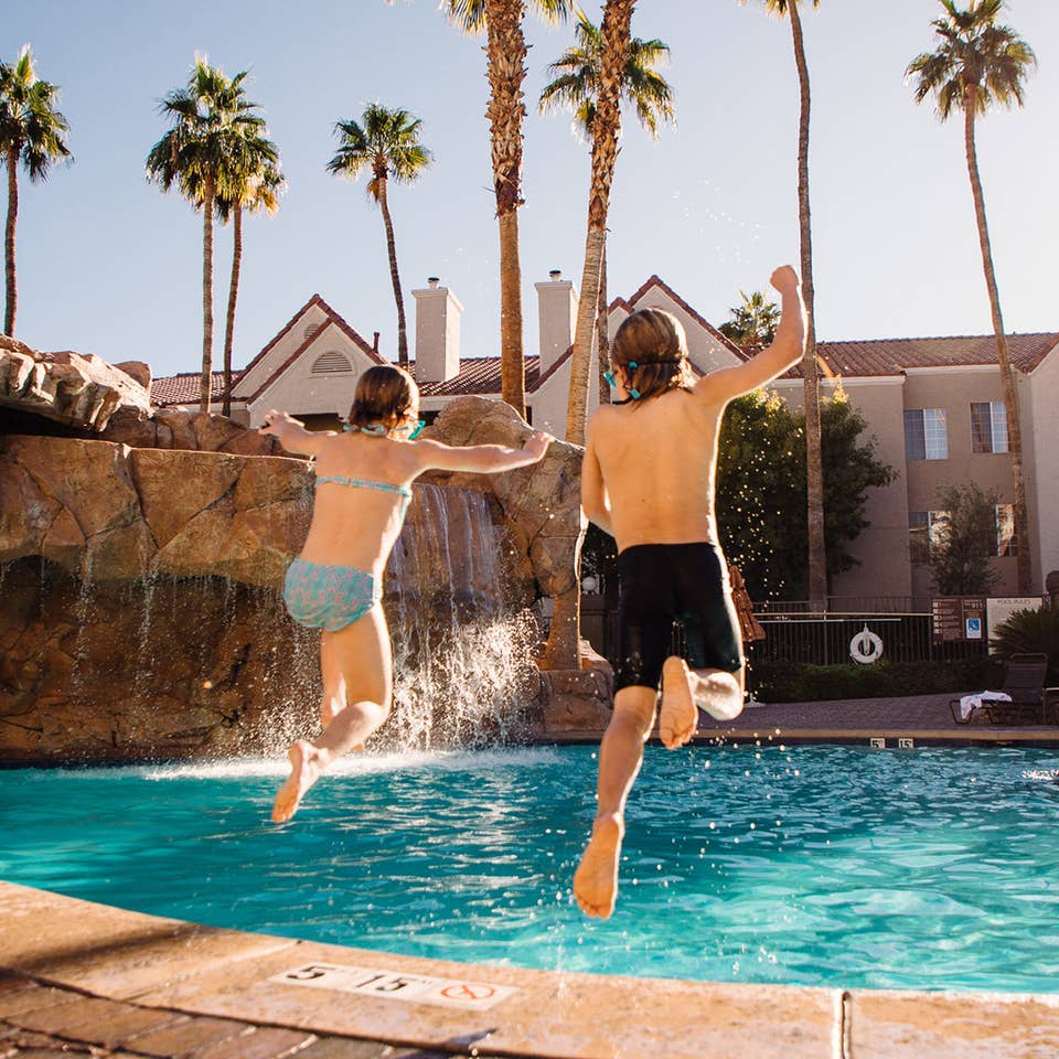 Two kids jumping into outdoor pool at Desert Club Resort in Las Vegas, Nevada