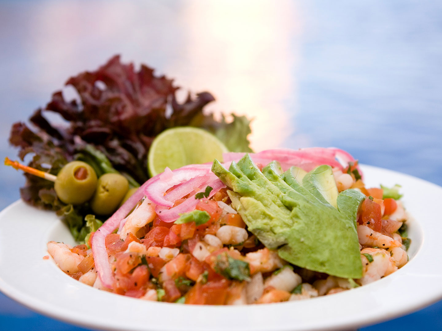 At the Sol Grill, shrimp ceviche topped with spices, cilantro, sliced avocado, pickled onions, green olives, leafy lettuce and a slice of lime, displayed in a white bowl, at The Royal Haciendas, in Playa del Carmen, Mexico
