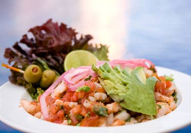 At the Sol Grill, shrimp ceviche topped with spices, cilantro, sliced avocado, pickled onions, green olives, leafy lettuce and a slice of lime, displayed in a white bowl, at The Royal Haciendas, in Playa del Carmen, Mexico