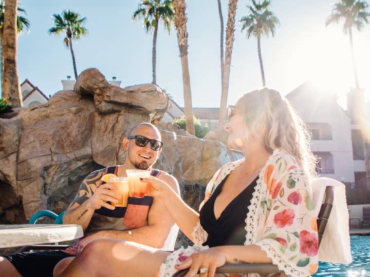Man and woman having drinks by outdoor pool at Desert Club Resort in Las Vegas, Nevada.
