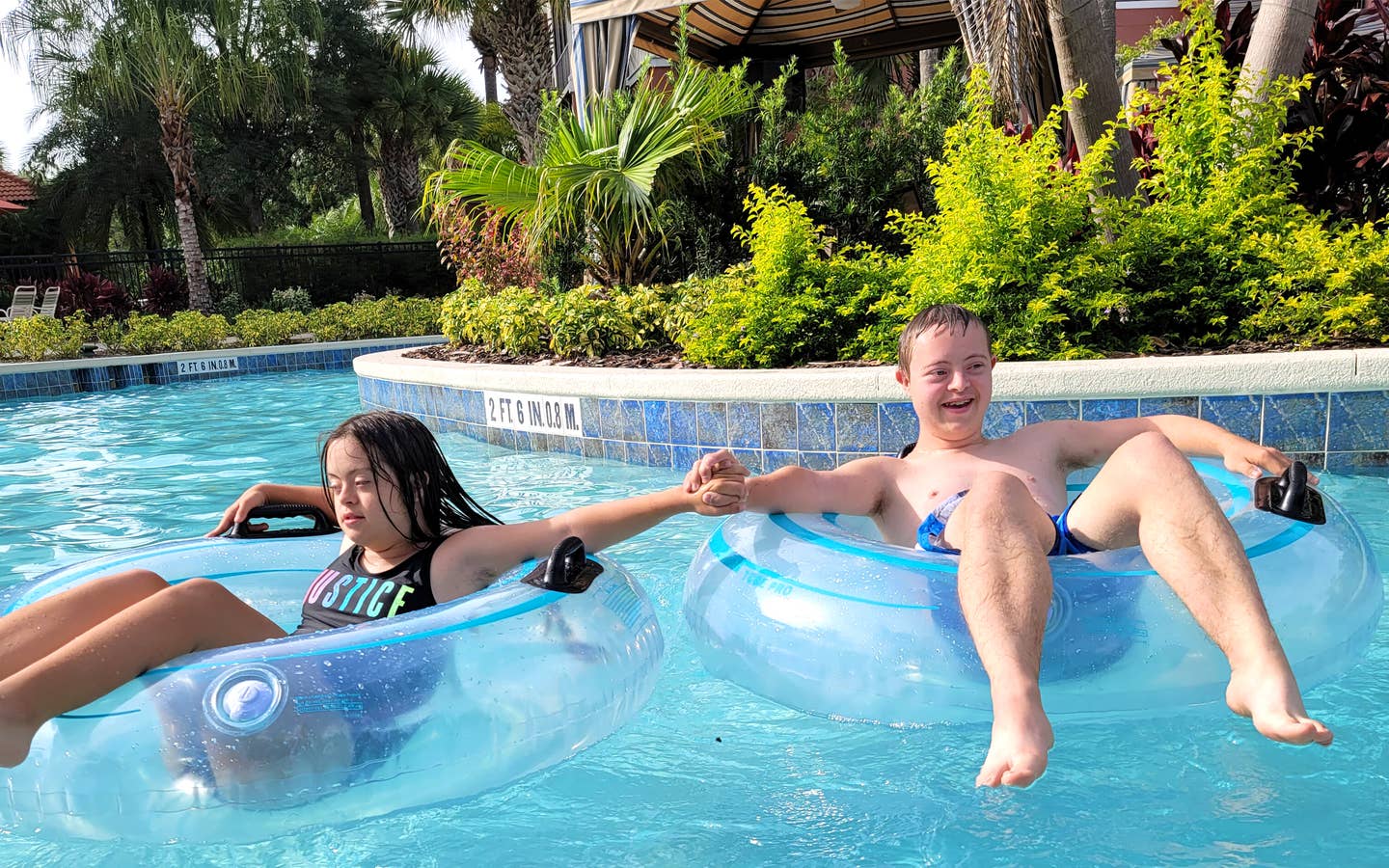 A young boy (right) and a young girl (left) sit in inner tubes while floating down a lazy river.
