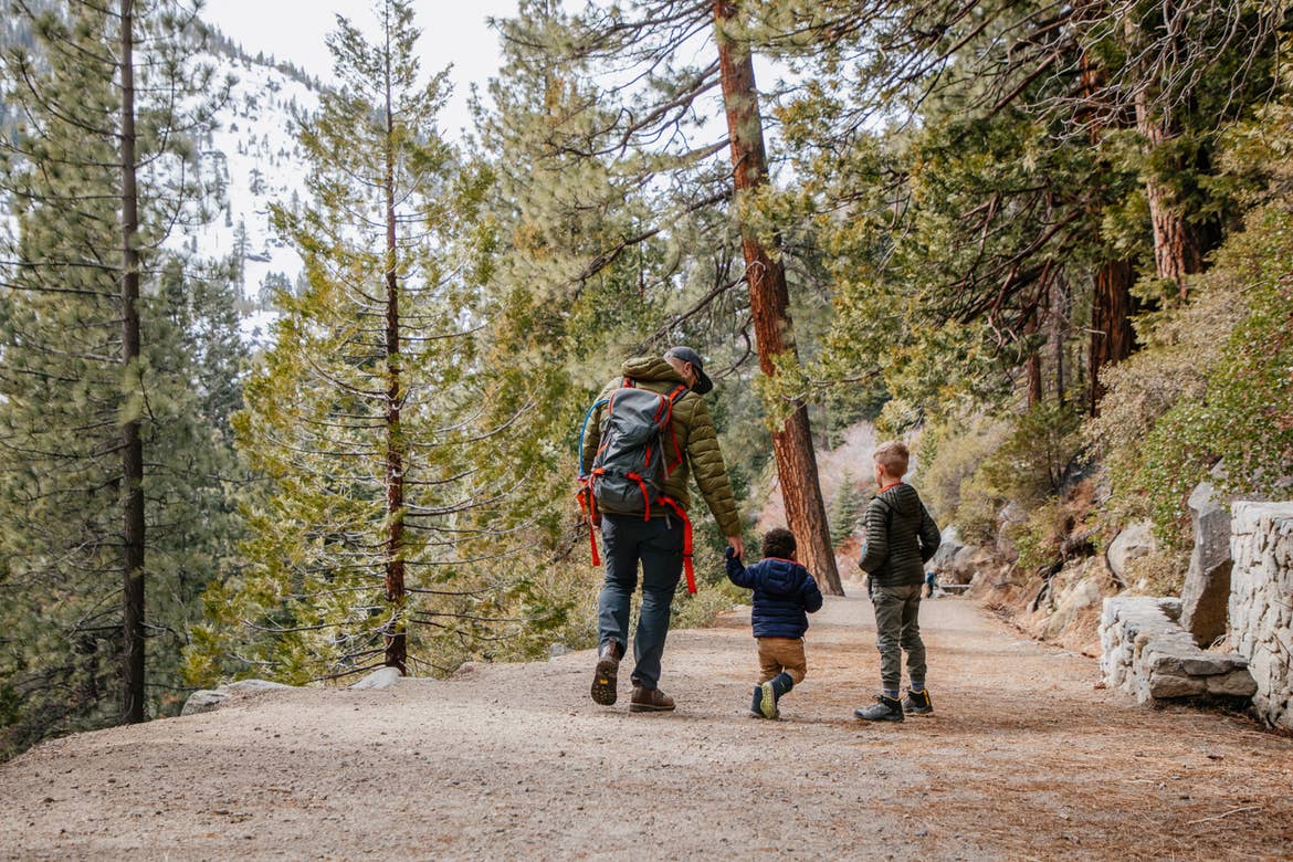 A family walks through Emerald Bay State Park with a gorgeous forest as a backdrop.