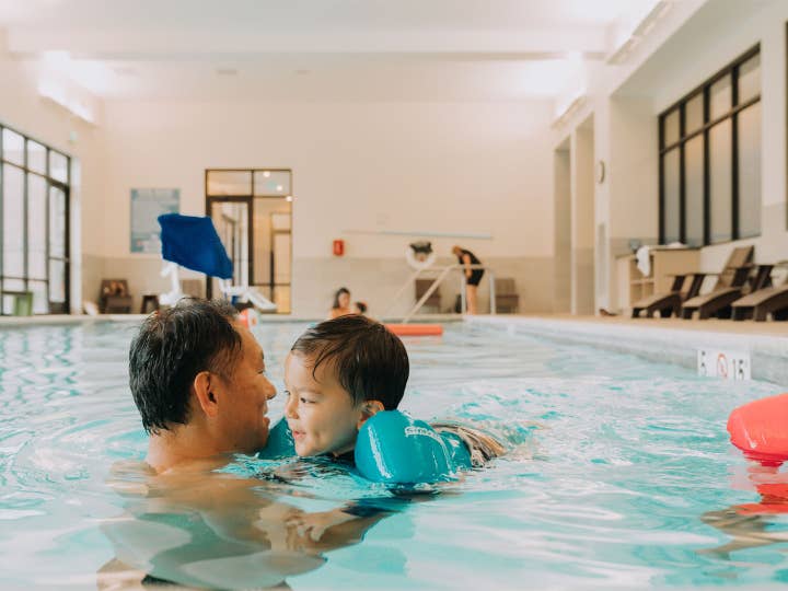 Adult and child swimming in indoor pool at Williamsburg Resort in Virginia.