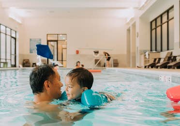 Adult and child swimming in indoor pool at Williamsburg Resort in Virginia.