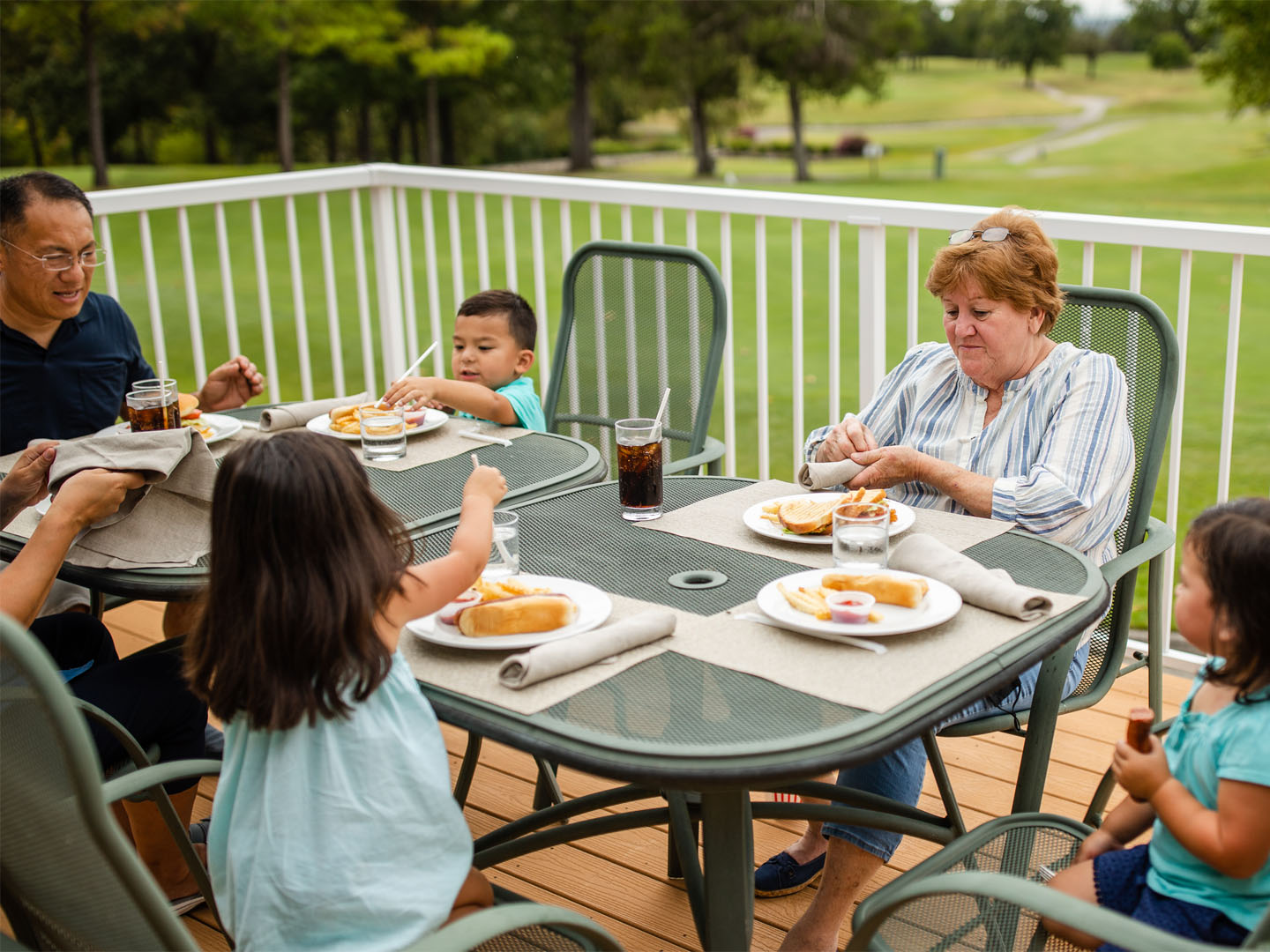 Family of six eating outdoors at The Grill on the Green at Holiday Hills Resort in Branson, Missouri.