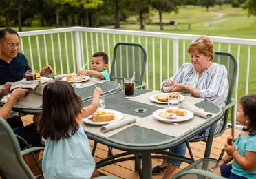 Family of six eating outdoors at The Grill on the Green at Holiday Hills Resort in Branson, Missouri.