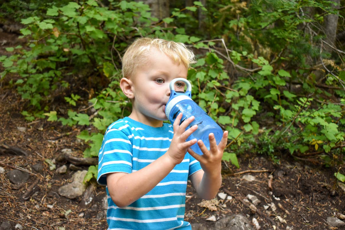 Jessica's son drinking from a water bottle during a hike break
