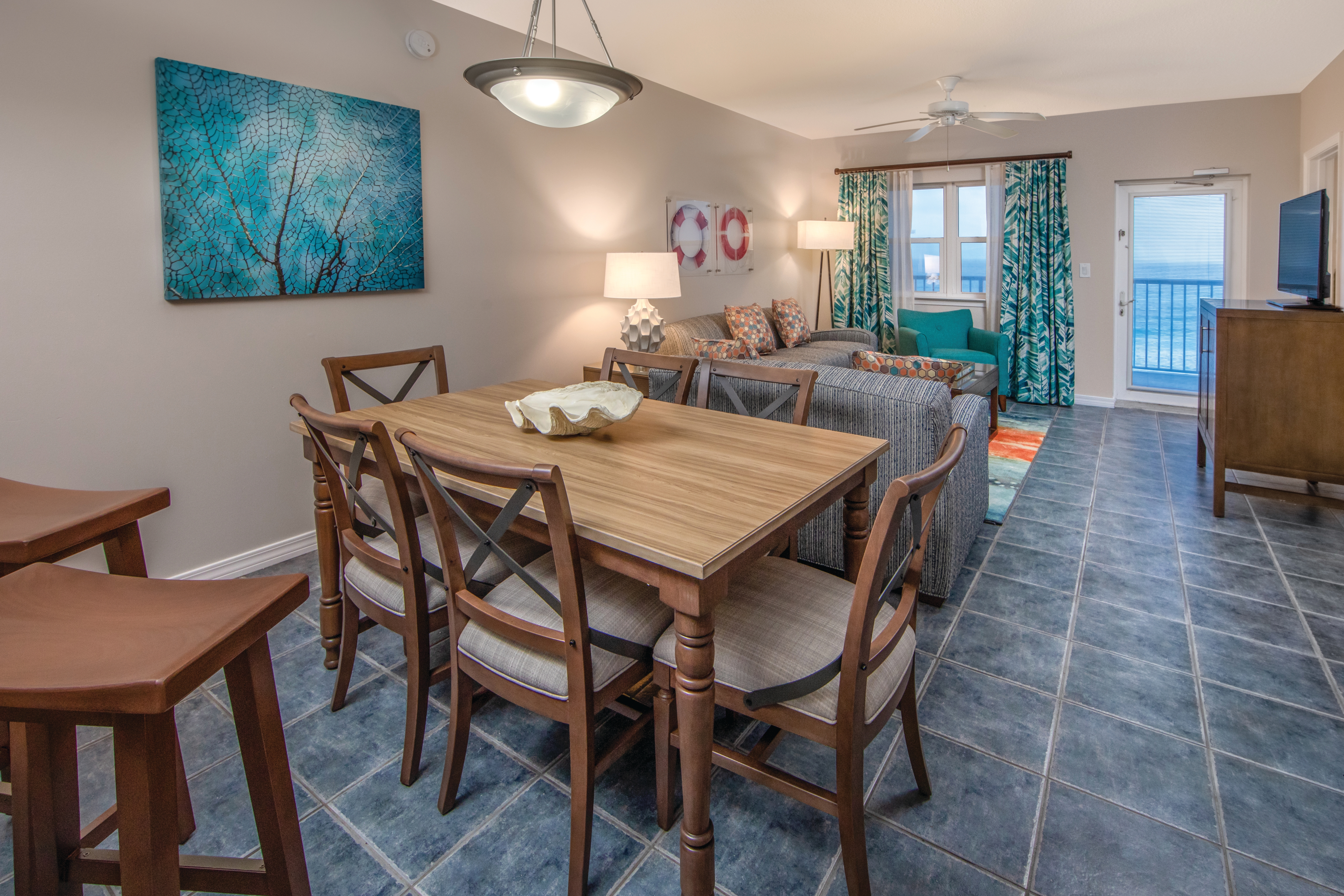 Dining room table with six chairs and view of living room in a two-bedroom villa at Panama City Beach Resort