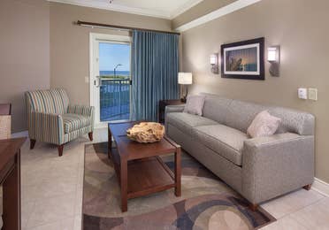 Living room with couch, accent chair, and access to balcony in villa at Galveston Beach Resort