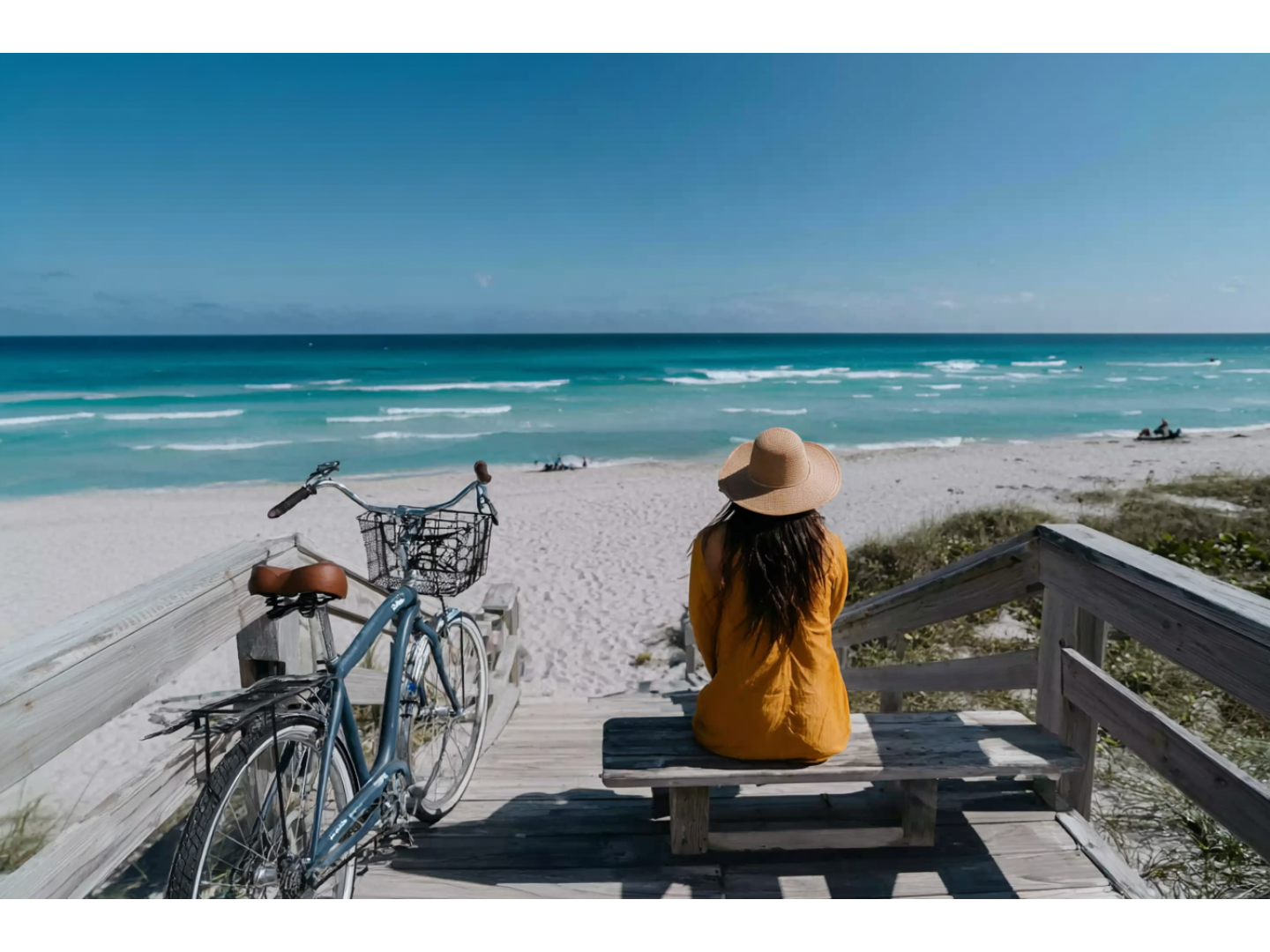 Woman relaxes on wooden beach walkway with bike parked next to her