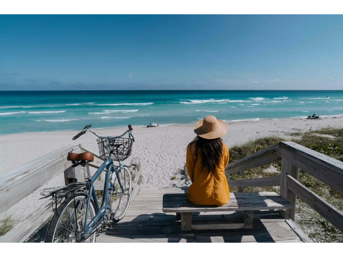 Woman relaxes on wooden beach walkway with bike parked next to her