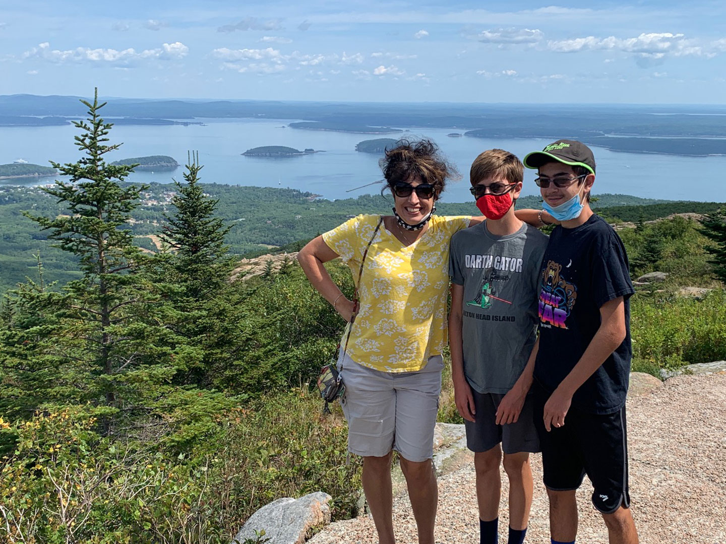 Author, Jennifer Probst (left), and her sons (middle and right) stand on the edge of the Acadia National Park hiking trail while wearing their masks.