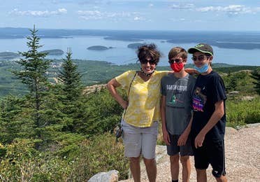 Author, Jennifer Probst (left), and her sons (middle and right) stand on the edge of the Acadia National Park hiking trail while wearing their masks.