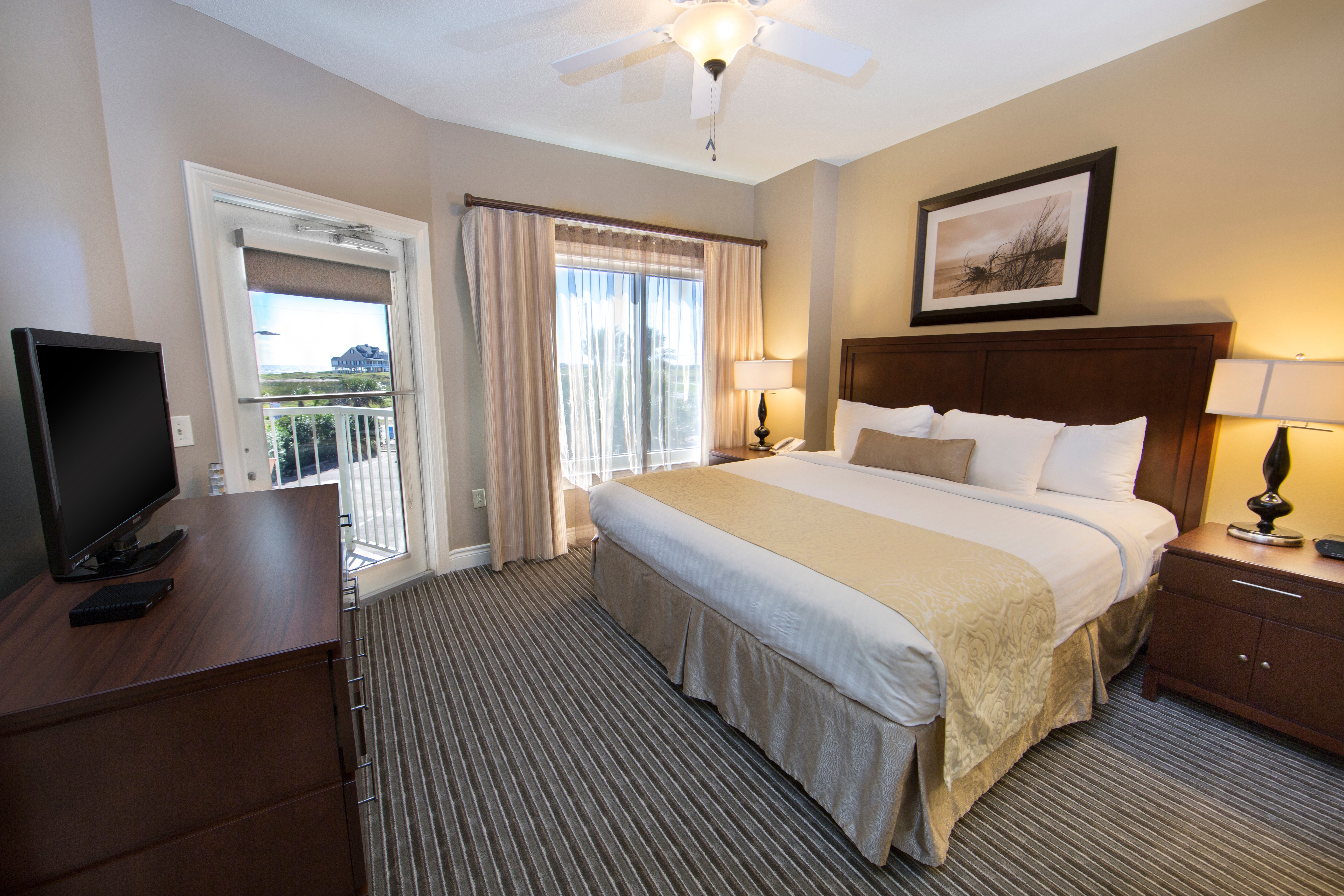 Master bedroom with king bed, flat screen TV, and large window in a one-bedroom villa at Galveston Beach Resort