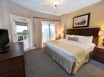 Master bedroom with king bed, flat screen TV, and large window in a one-bedroom villa at Galveston Beach Resort