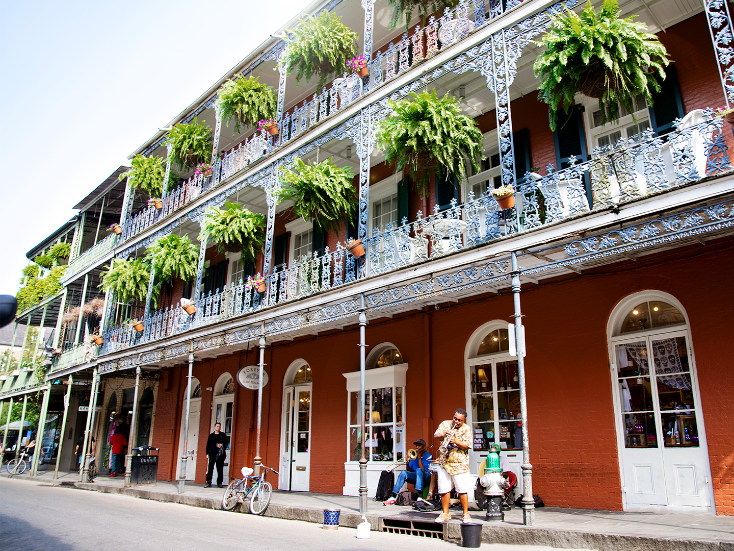Bourbon Street under a sunny blue sky with street performers near New Orleans Resort.