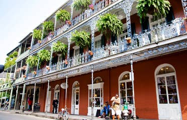Bourbon Street under a sunny blue sky with street performers near New Orleans Resort.